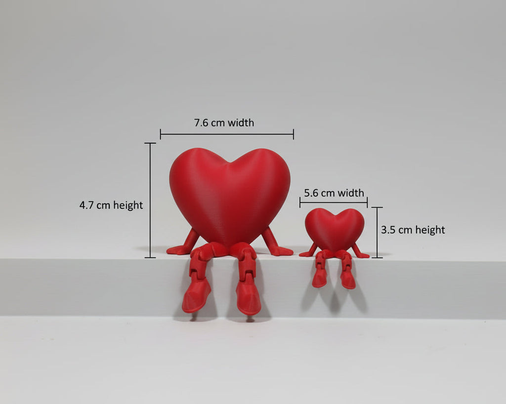 Two red heart-shaped figures sitting on a white surface with a light gray background